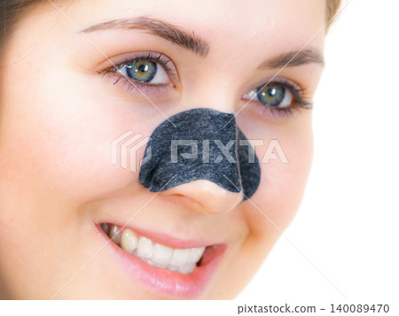 Woman applying pore strips on nose Woman applying pore strips on nose 140089470