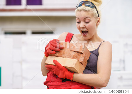 Funny woman carrying heavy bricks Funny woman carrying heavy bricks 140089504
