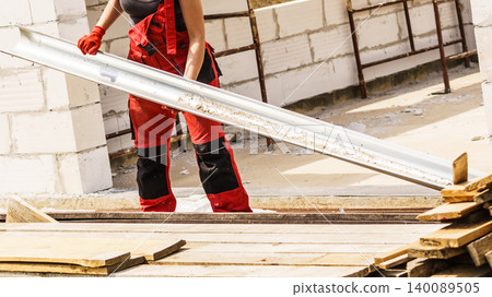 Person carrying gutter on construction site Person carrying gutter on construction site 140089505