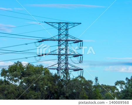 A large electricity transmission tower surrounded by trees on a hill A large electricity transmission tower surrounded by trees on a hill 140089568