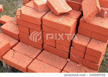 Red ceramic bricks stacked on a wooden pallet at a construction site. High-quality clay building blocks, ready for wall construction, home renovation Red ceramic bricks stacked on a wooden pallet at a construction site. High-quality clay building blocks, ready for wall construction, home renovation 140089769