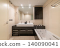 Modern bathroom with a sleek design. Features a large white sink, black cabinetry, a bathtub, and bright lighting. Clean and minimalist aesthetic. 140090041