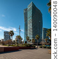 Modern skyscrapers surrounded by palm trees under a clear blue sky. Urban landscape showcasing contemporary architecture and greenery. 140090048
