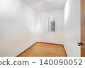 Empty room with white walls and wooden floor. A small window allows natural light to enter. The space is minimalistic and uncluttered. 140090052
