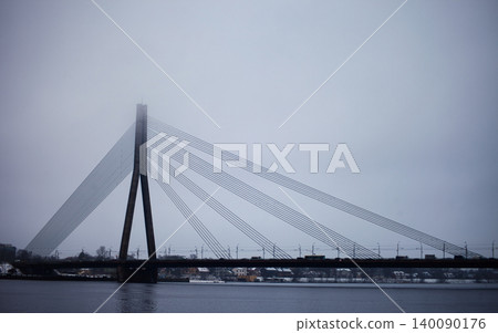 Cabled-stayed bridge over a wide river on a misty day Cabled-stayed bridge over a wide river on a misty day 140090176