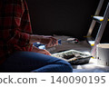 Woman holds paint roller near tray, bucket and ladder beside dark wall 140090195