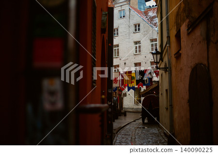 Atmospheric view of a narrow medieval cobblestone alleyway decorated with heraldic flags and banners Atmospheric view of a narrow medieval cobblestone alleyway decorated with heraldic flags and banners 140090225