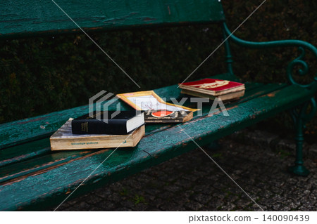 Old books left on a green wooden bench in a park 140090439