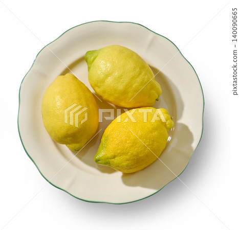 Three Fresh Lemons on a Decorative Ceramic Plate Isolated on White. Top View 140090665