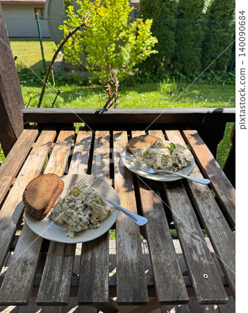 Meat and Potato Salad with Rye Bread Slice on Sunny Wooden Table. Meat and Potato Salad with Rye Bread Slice on Sunny Wooden Table. 140090684