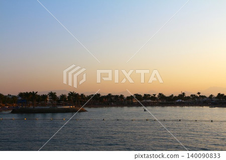 Tropical Sunset Over Calm Ocean with Resort and Palm Trees Tropical Sunset Over Calm Ocean with Resort and Palm Trees 140090833