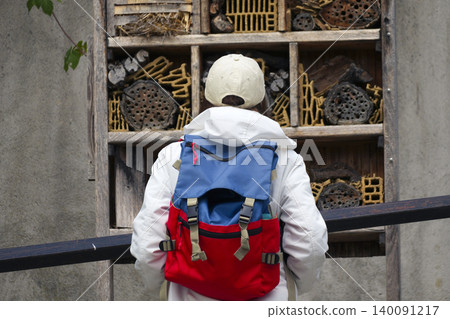 Young woman looking at an insect hotel, emphasizing eco friendly garden infrastructure and urban nature support. 140091217
