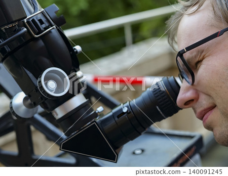 Person looking through an astronomical telescope eyepiece, illustrating hands on optical exploration while learning the sky. Person looking through an astronomical telescope eyepiece, illustrating hands on optical exploration while learning the sky. 140091245