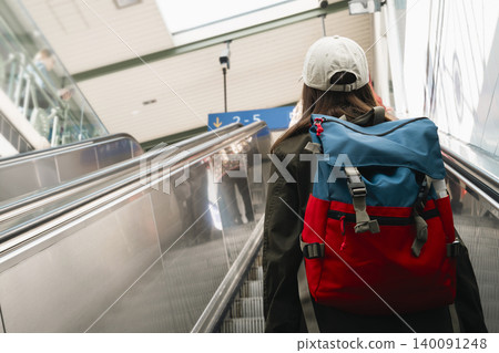 Young woman with a backpack on an escalator at a railway station, highlighting modern travel and transit infrastructure. Young woman with a backpack on an escalator at a railway station, highlighting modern travel and transit infrastructure. 140091248