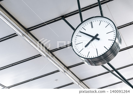 Large round clock hanging at a railway station, symbolizing accurate timekeeping in major transportation hubs. Large round clock hanging at a railway station, symbolizing accurate timekeeping in major transportation hubs. 140091264