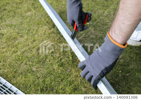Maintenance task of a metal outdoor drain grate, focusing on proper safety gear and careful handling. Maintenance task of a metal outdoor drain grate, focusing on proper safety gear and careful handling. 140091306