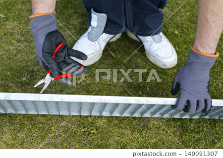 A person wearing gloves holds a pliers during a drain grate maintenance, focusing on proper safety gear and careful handling A person wearing gloves holds a pliers during a drain grate maintenance, focusing on proper safety gear and careful handling 140091307