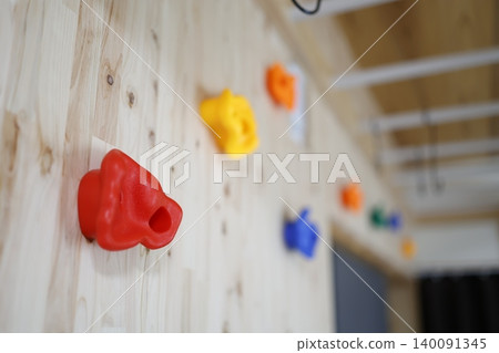 Colorful bouldering holds on a wooden wall installed at home. Colorful bouldering holds on a wooden wall installed at home. 140091345
