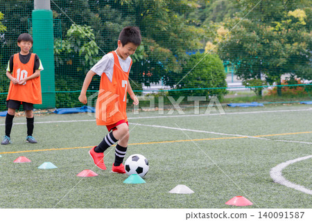 A young soccer player practicing dribbling A young soccer player practicing dribbling 140091587
