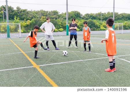 A boys' team and their male coach practice passing during futsal training. A boys' team and their male coach practice passing during futsal training. 140091596
