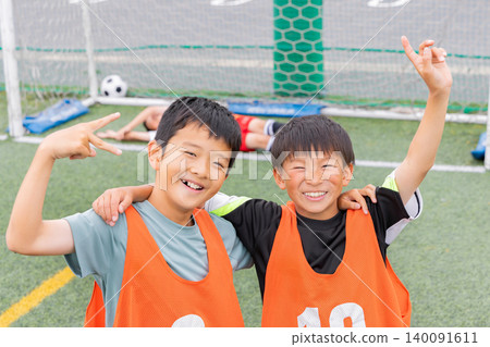 Boys smiling and putting their arms around each other's shoulders after scoring a goal in soccer. Boys smiling and putting their arms around each other's shoulders after scoring a goal in soccer. 140091611