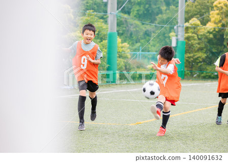 Young soccer players aim for the goal with a shot after dribbling. 140091632