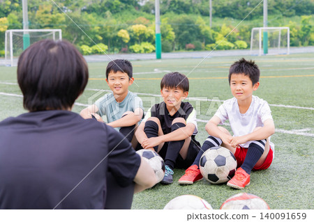 Boys holding a huddle meeting with their soccer coach. Boys holding a huddle meeting with their soccer coach. 140091659