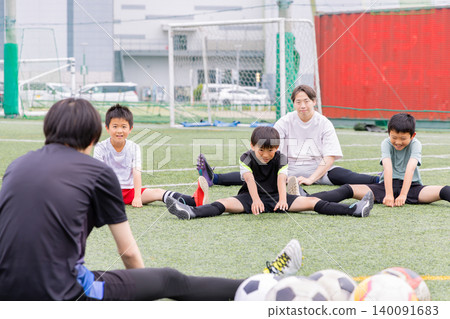 A boys' futsal team and their male coach stretching during practice. A boys' futsal team and their male coach stretching during practice. 140091683