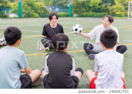 A male coach and some boys explaining their strategy on a futsal court. A male coach and some boys explaining their strategy on a futsal court. 140091701