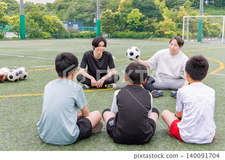 A male coach and some boys explaining their strategy on a futsal court. A male coach and some boys explaining their strategy on a futsal court. 140091704