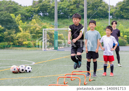 男孩們在五人制足球訓練期間，和他們的男教練一起進行梯子訓練。 140091713