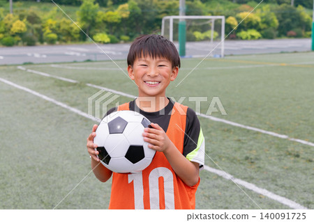 A young athlete smiles while holding a soccer ball. A young athlete smiles while holding a soccer ball. 140091725