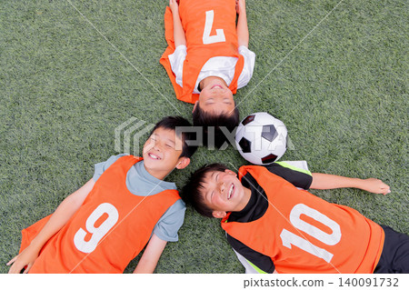 Smiling faces of a boys' team lying on the soccer field 140091732