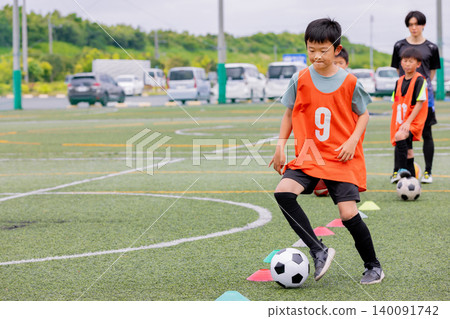 A male coach and some boys giving dribbling instruction during futsal practice. A male coach and some boys giving dribbling instruction during futsal practice. 140091742