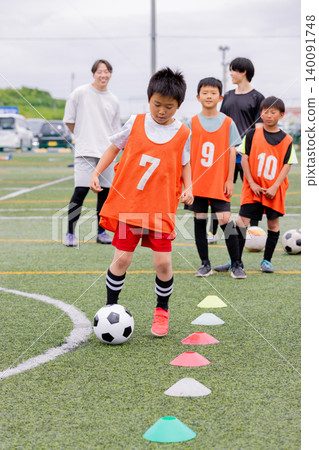 A male coach and some boys giving dribbling instruction during futsal practice. 140091748