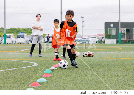 一名男教練和一些男孩在五人制足球訓練中進行運球指導。 一名男教練和一些男孩在五人制足球訓練中進行運球指導。 140091751
