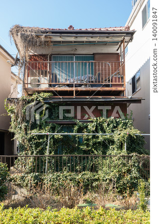 An old, vacant house covered in ivy and two dilapidated houses An old, vacant house covered in ivy and two dilapidated houses 140091847
