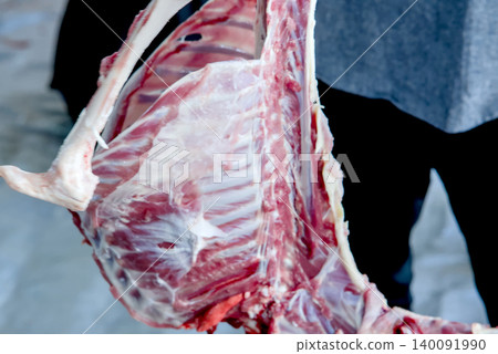 Butcher chopping raw meat with a cleaver on a wooden cutting board Butcher chopping raw meat with a cleaver on a wooden cutting board 140091990