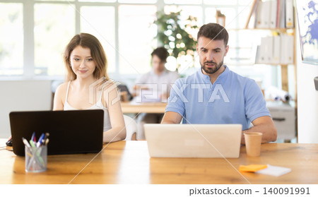 Man and girl staff colleagues working at laptop computer in office room space 140091991