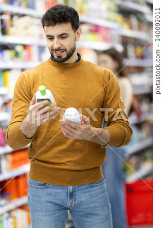 Male shopper is shopping in a supermarket, buying body care products Male shopper is shopping in a supermarket, buying body care products 140092011