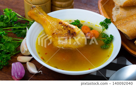 Broth with chicken leg in white bowl Broth with chicken leg in white bowl 140092040