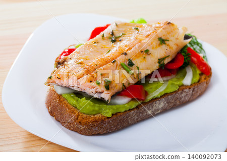 Tasty sandwich with trout, guacamole, red pepperand greens at plate Tasty sandwich with trout, guacamole, red pepperand greens at plate 140092073