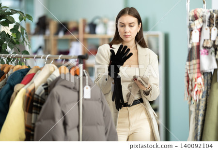Young woman choosing gloves in clothing store Young woman choosing gloves in clothing store 140092104
