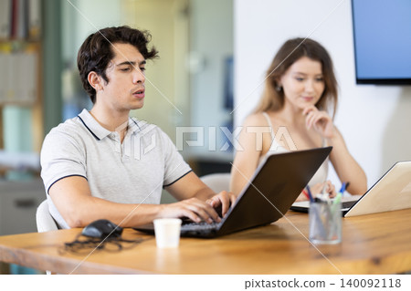 Man and girl staff colleagues working at laptop computer in office room space 140092118