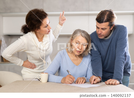 Adult children help and tell old mother how to make testament while at home in kitchen Adult children help and tell old mother how to make testament while at home in kitchen 140092137