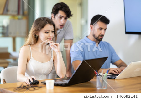 Group of managers discussing around laptop at office table 140092141