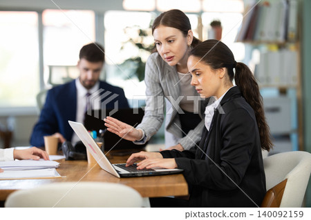 Young girl helping colleague with tasks on laptop Young girl helping colleague with tasks on laptop 140092159