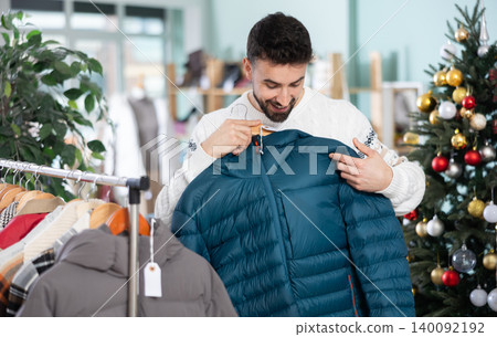 In store, man customer choose down jacket. X mas shopping In store, man customer choose down jacket. X mas shopping 140092192