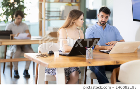 Girl helps guy complete task on laptop Girl helps guy complete task on laptop 140092195