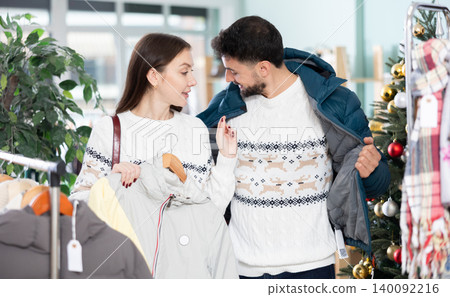 In store, man try on down jacket in presents of wife, X mas shopping In store, man try on down jacket in presents of wife, X mas shopping 140092216